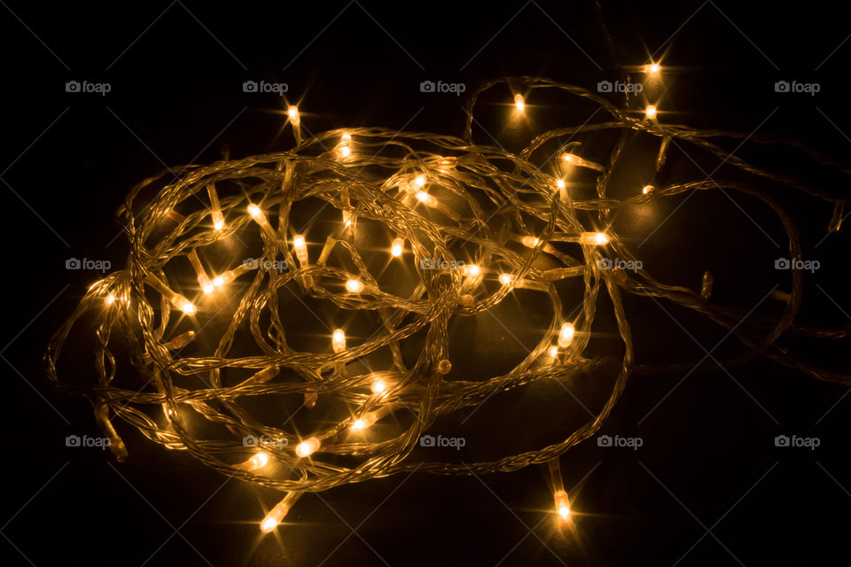 Diwali chain light, spiral shape, design to decorate street or home fireworks, dark black background shot in festival time or new years eve carnival, copy space. Remove darkness, decoration concept