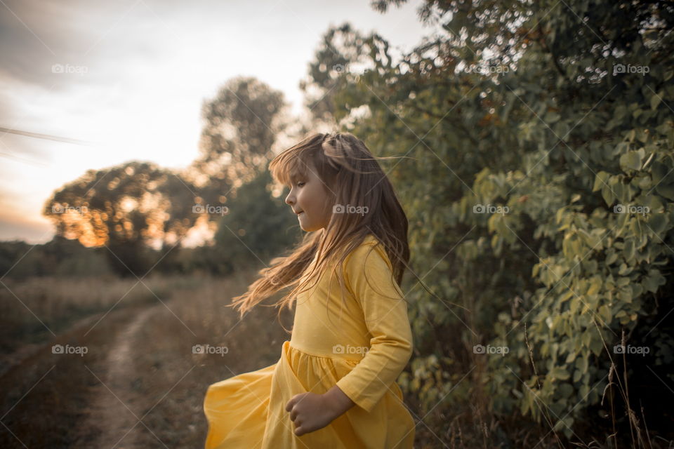 Little girl in yellow dress outdoor portrait at sunset 