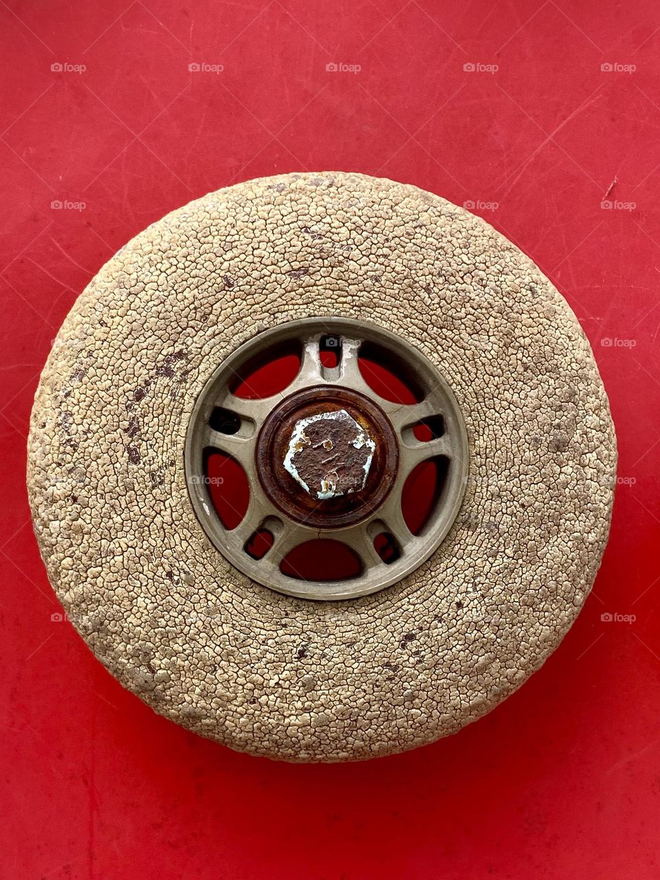 Close up of an old cracked rollerblade wheel on a bright red background