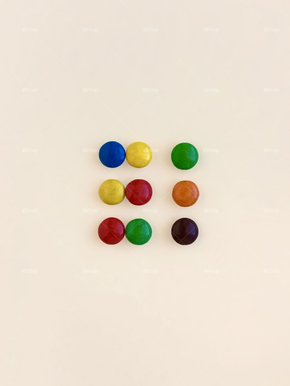 multicolored candies laid out in the shape of a square on a beige background