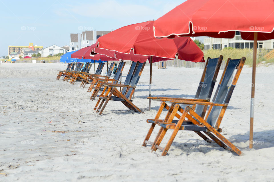 Row of lounge chairs and umbrellas set up on the beach with no people