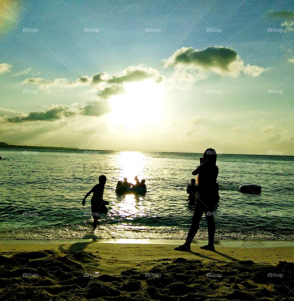 White sands beach, relaxing Sunny Day, kids swimming and playing in waters.