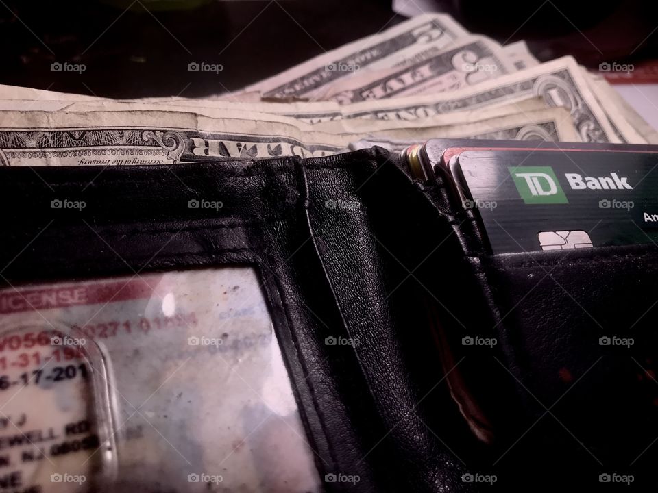 The contents of a middle class wallet. Credit cards and money with id  shot up close with high contrast and sharp detail 