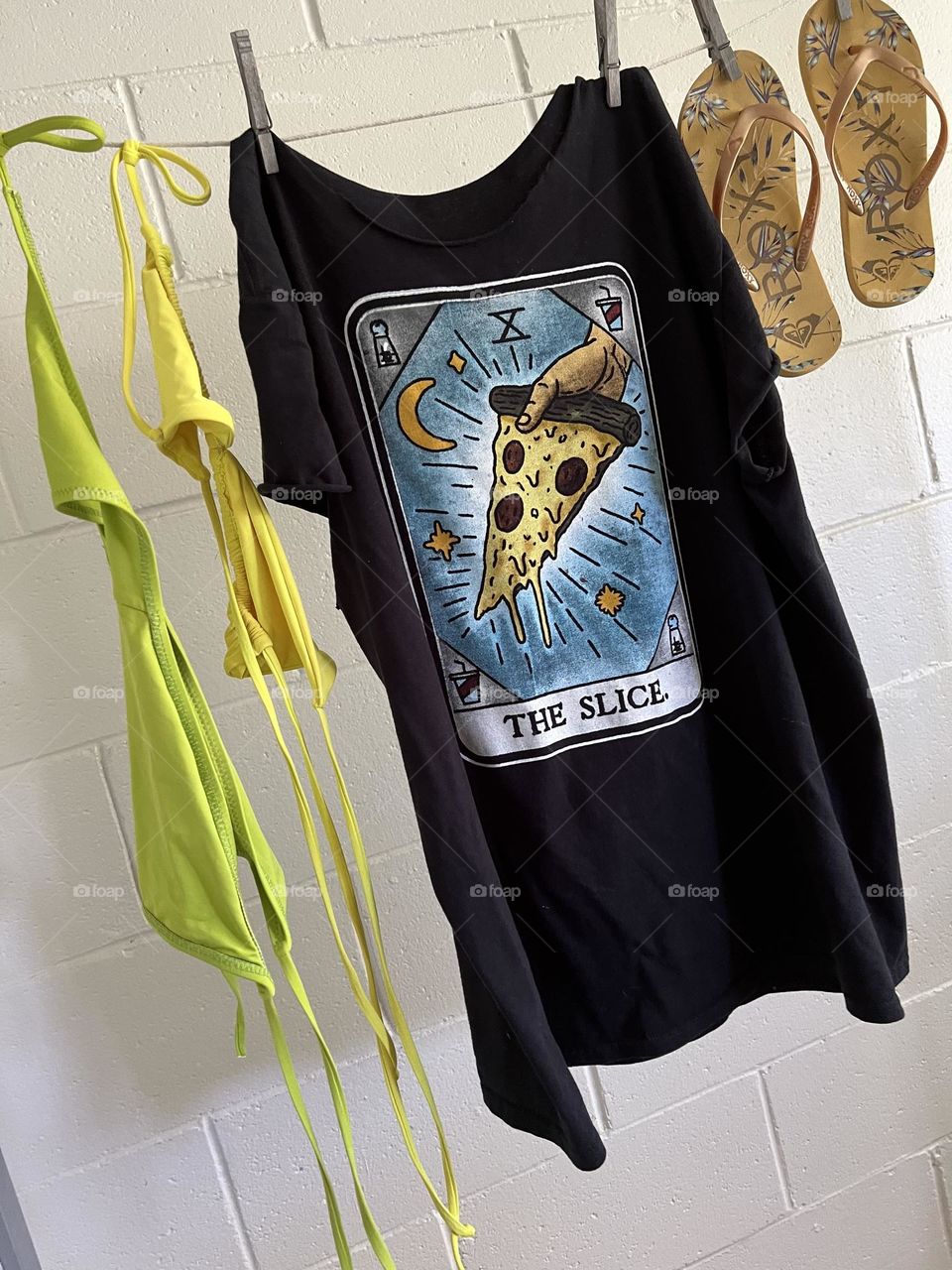 Summer beach essential wardrobe is a men’s XL black T-shirt with a modified Rider-Waite tarot card featuring “The Slice” and my yellow and chartreuse bikini, plus floral gold and mustard flip flops from Roxy