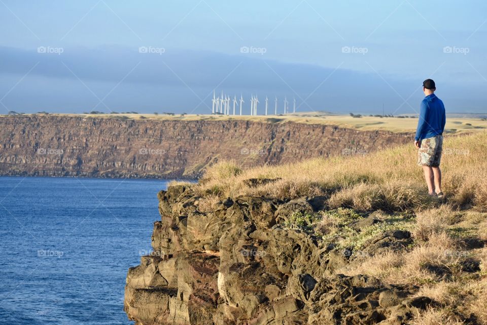 Walking by the sea cliffs with wind turbines in the distance