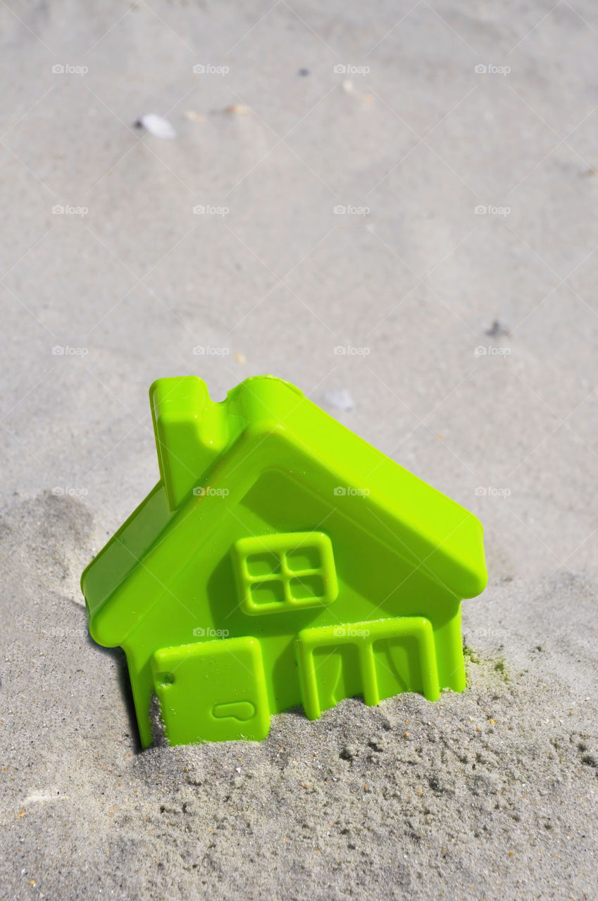 Beach house concept. Childs toy beach house in the sand. 