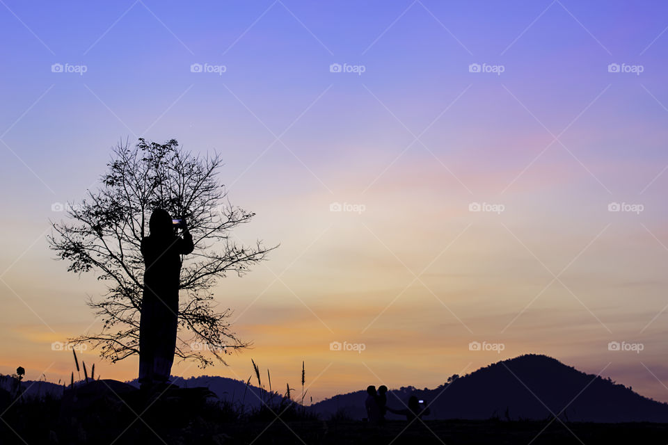 Tourists photograph the sunrise  behind the mountains.