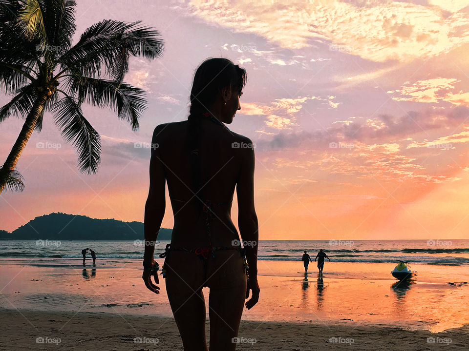 Silhouette of a young woman at the tropical beach in the evening 