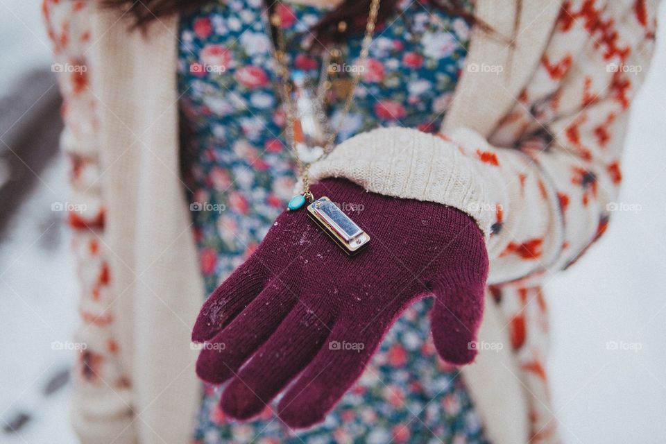 Close-up of woman's hand holding tiny harmonica in her hand