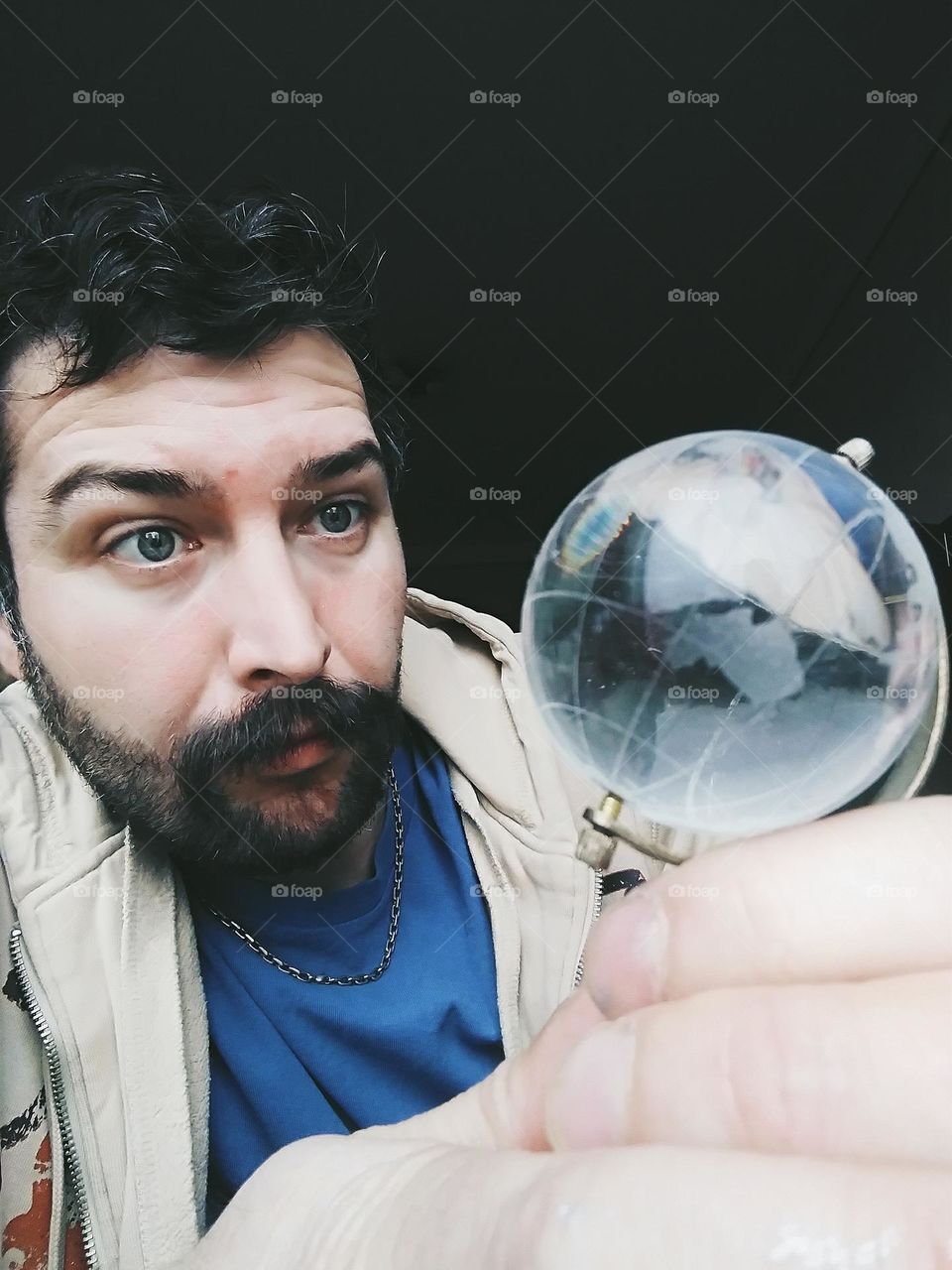 a man with a beard and a small glass globe of the earth