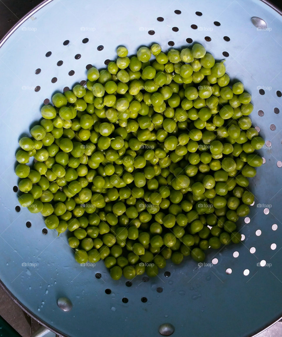Freshly prepared green peas in a blue colander