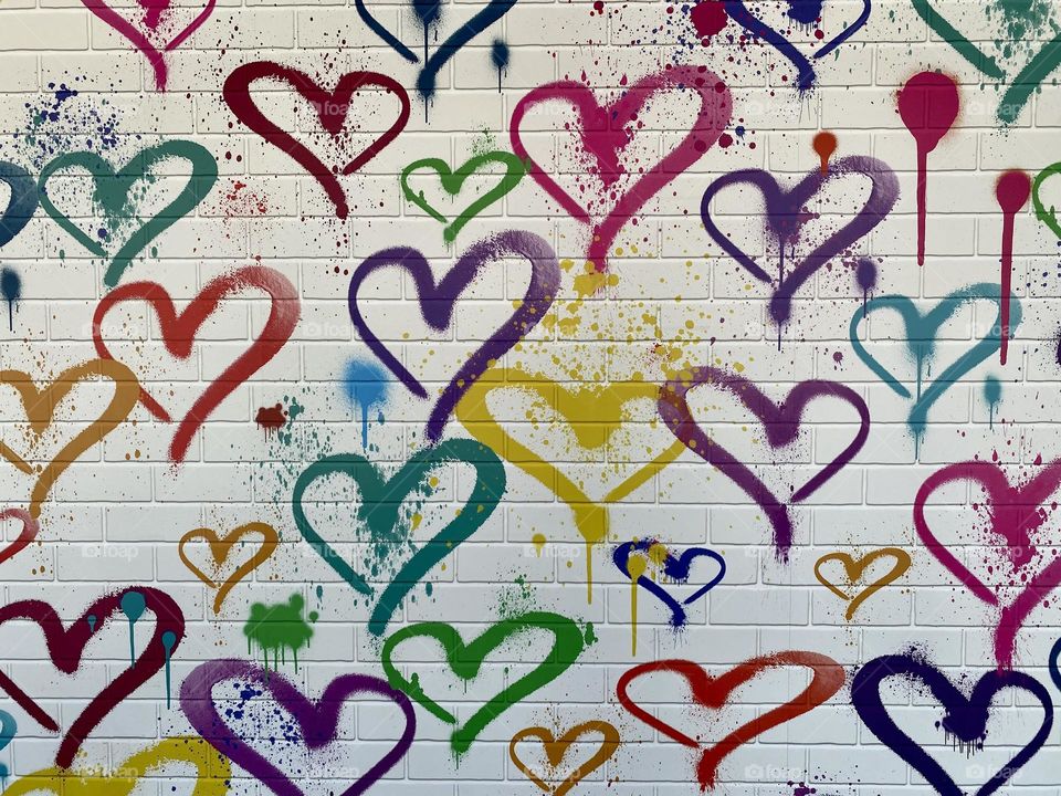 Colorful hearts painted on a white brick wall