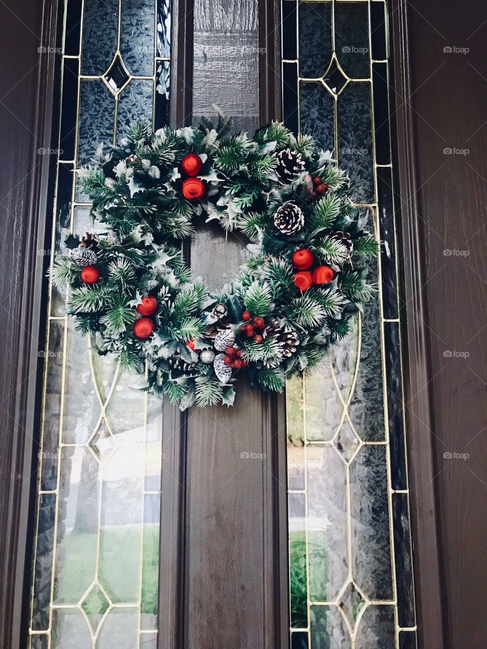 A green and red holy berry Christmas wreath on the front door on a cool crisp winters day. USA, America 