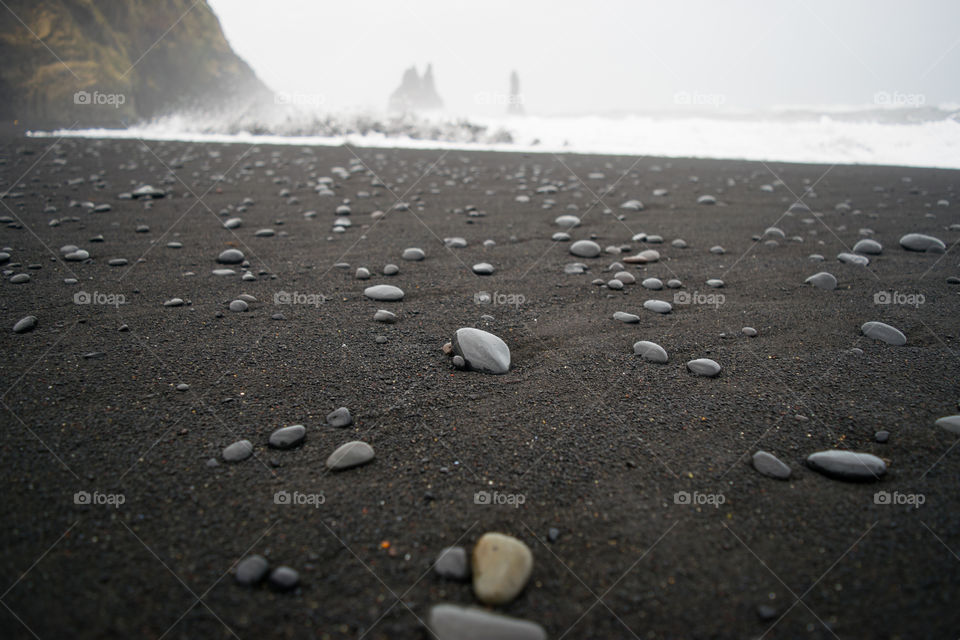 Stones that stand out among the sand of a black beach on the coast of Iceland