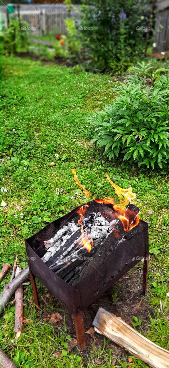костер горит в мангале на зеленой траве