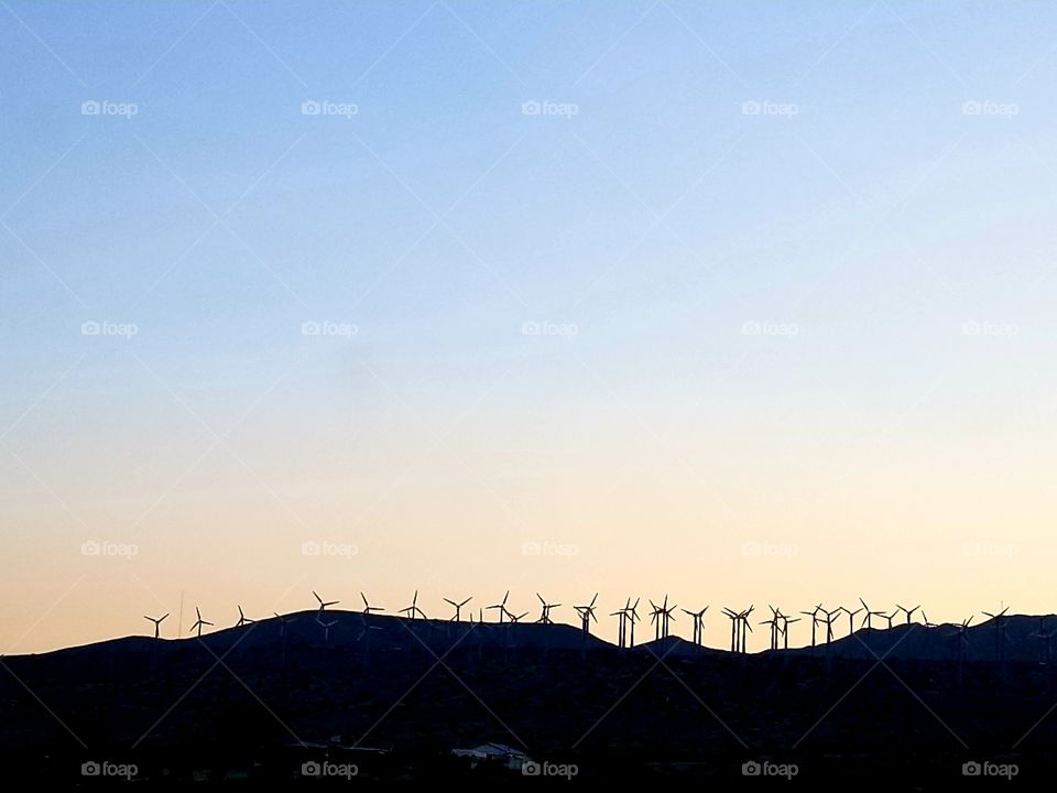 Wind turbine silhouettes line the ridge at sunset