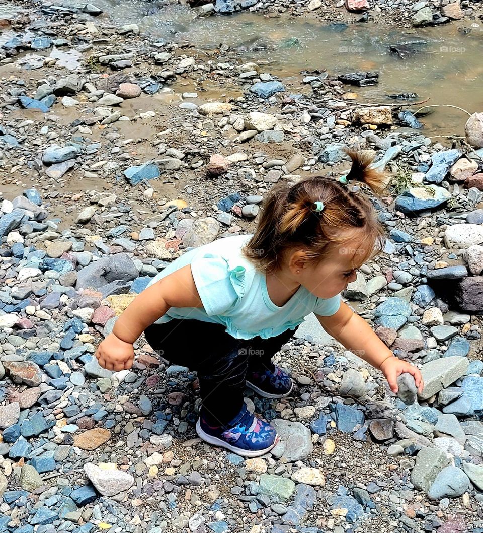 niña juega con piedritas del río