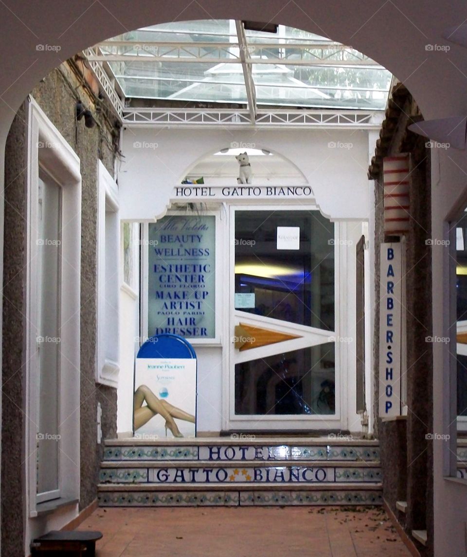 Brightly lit entrance to an Italian hotel with modern glass door and elegant tile work