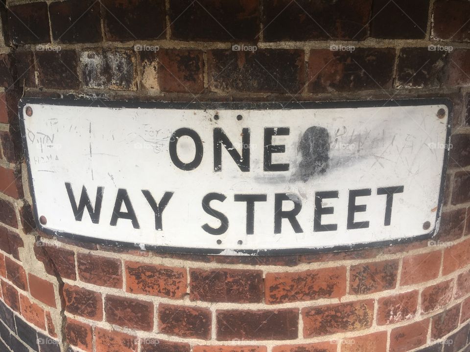 One Way Street sign on curved brick wall at the junction of Hodford Road and Accommodation Road in Golders Green, London, discovered on a Sunday afternoon in Summer