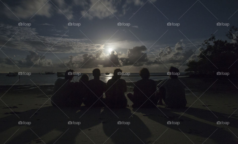 Friends by the beach contemplating the moon 