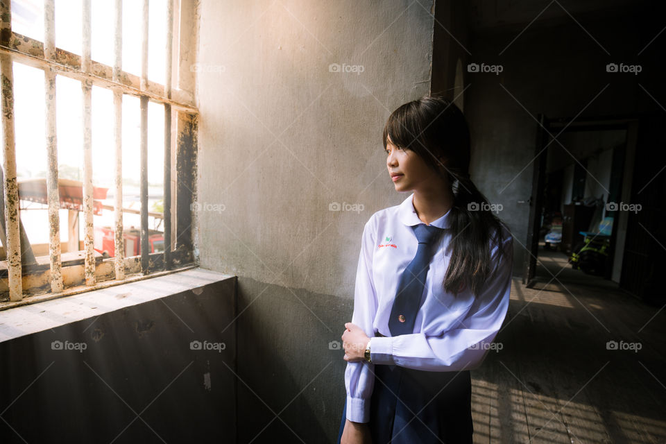 Girl student looking out of the window with light coming in