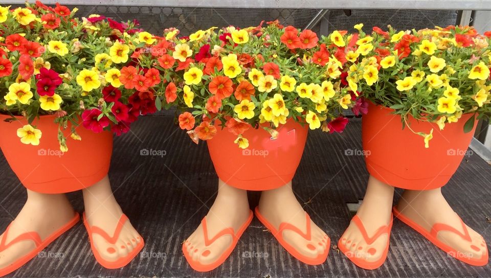 Bright orange flower pots for sale with flip flop feet for stands.