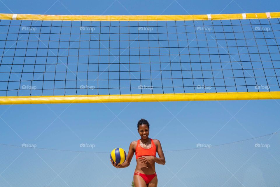 Beautiful black woman with Afro hair playing volleyball at the beach