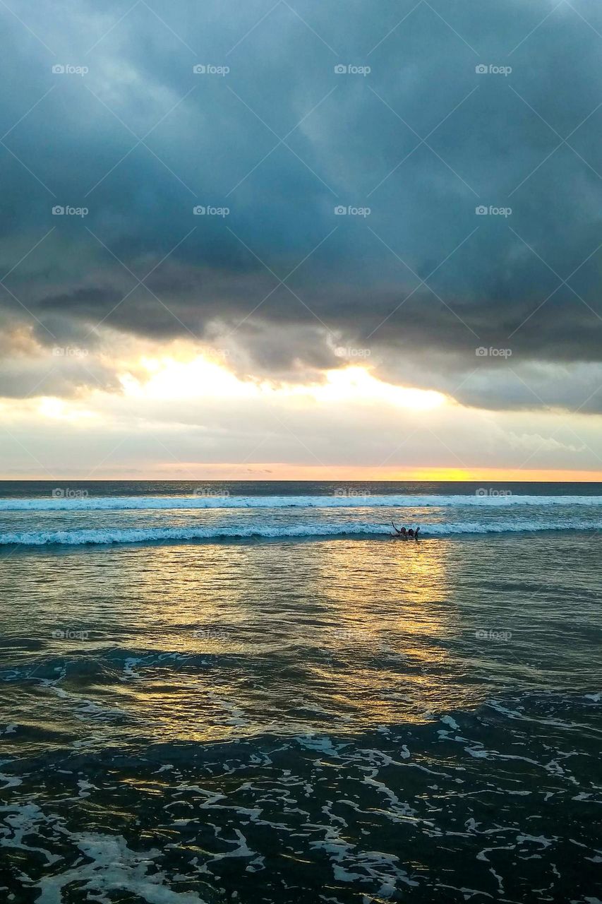 Children swimming on a cloudy beach illuminated by the afternoon sun in eye level view