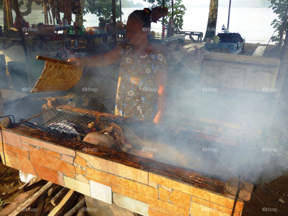 old woman making smokes fish