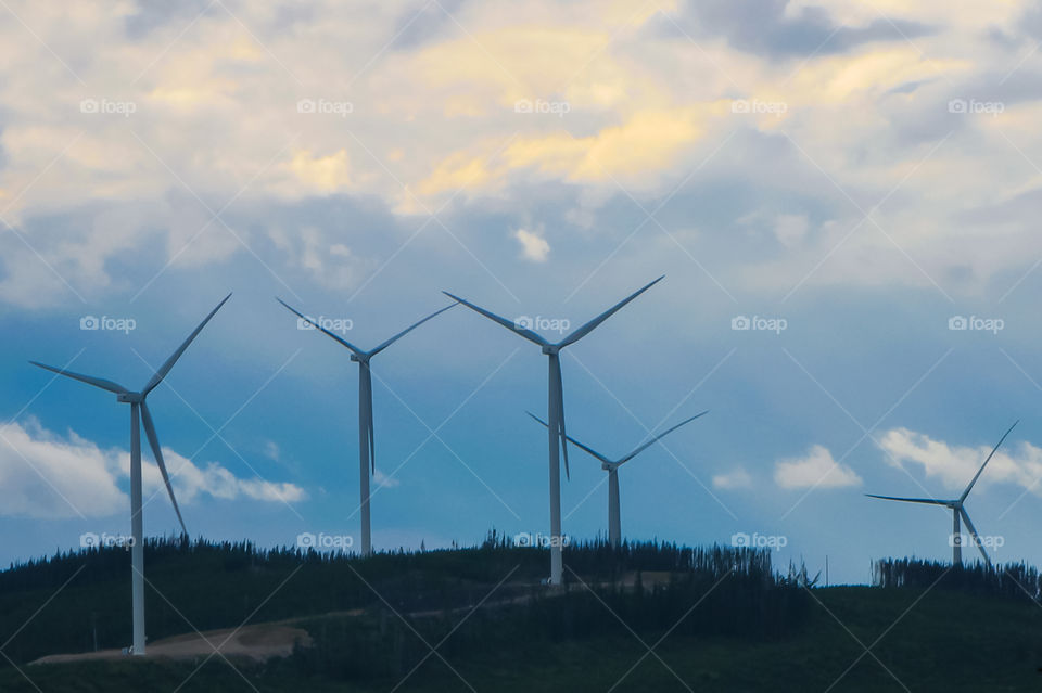Leading lines, rule of odds: Five wind generators all nearly perfectly aligned in a ‘Y’ as if their ‘arms’ are stretching up to the sunlight above the dark blue clouds.