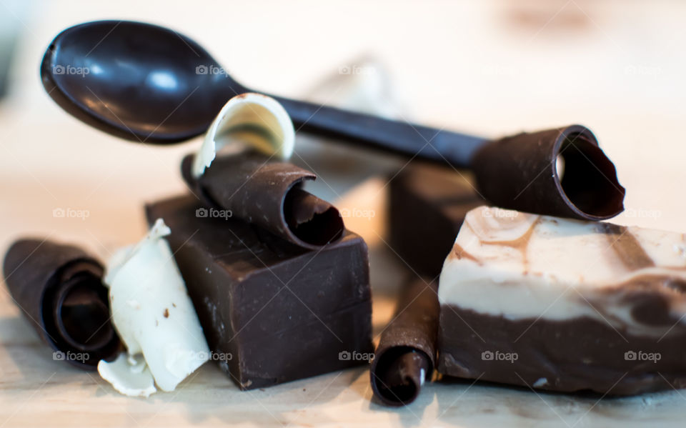 Spoon made of dark chocolate on top of pile of chocolate fudge and white and dark chocolate shavings ingredients for gourmet chocolate making conceptual photography 