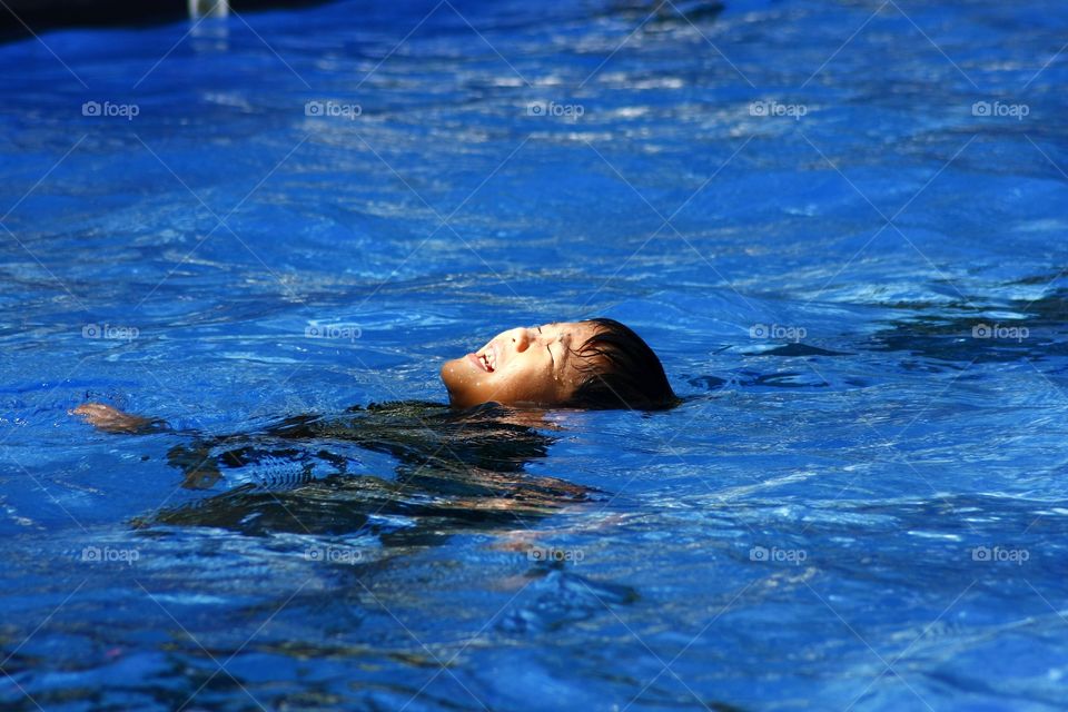 young boy learning how to float on water