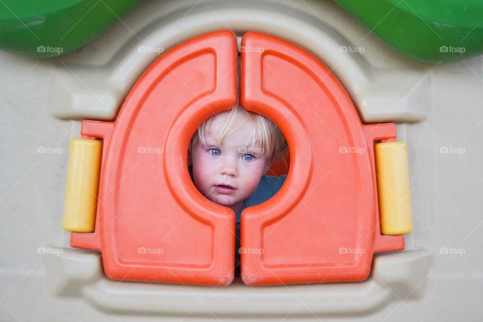 Cute boy playing in toy house