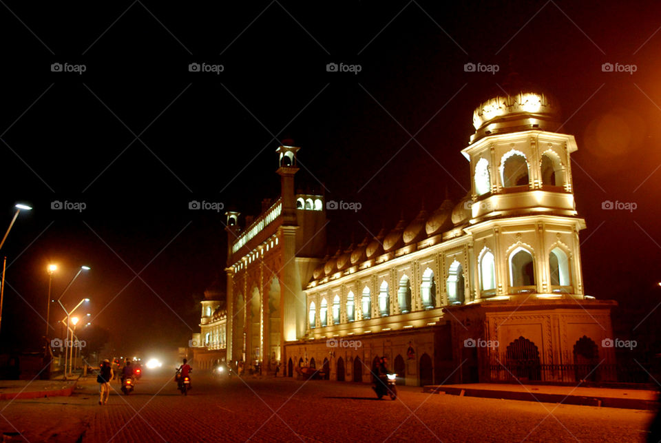 Night shot of historical palatial complex with arches and minarets in perspective.