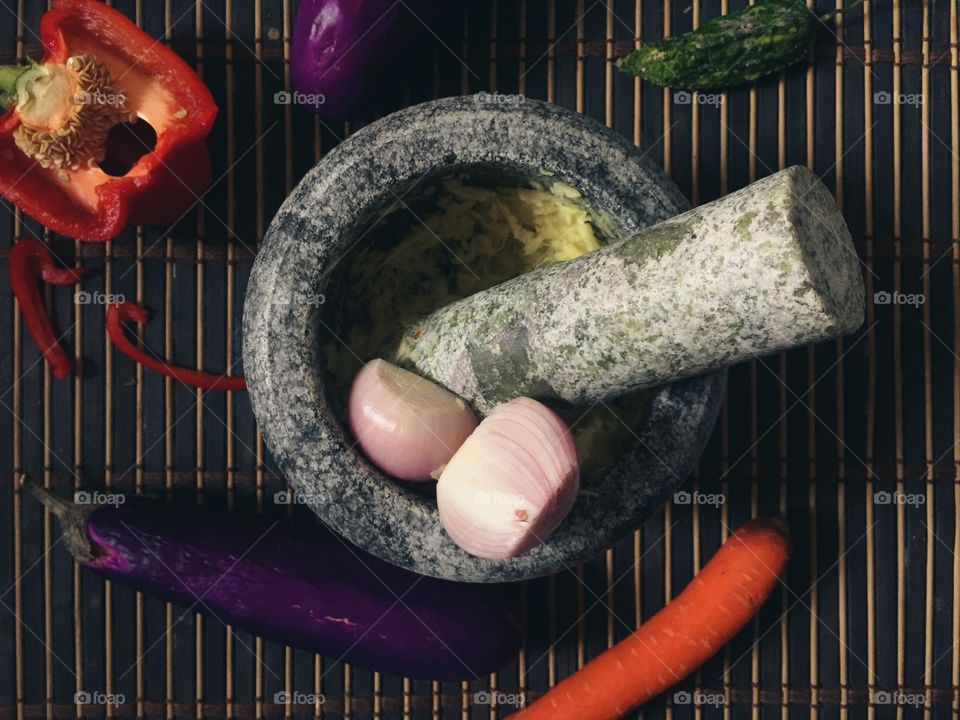 Home food preparation with pestle and mortar, capsicum, garlic, carrot, ginger, and onions. 