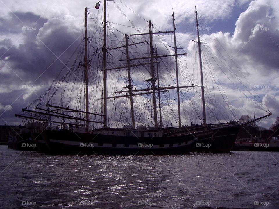 A sailing ship on the water against the cloudy sky