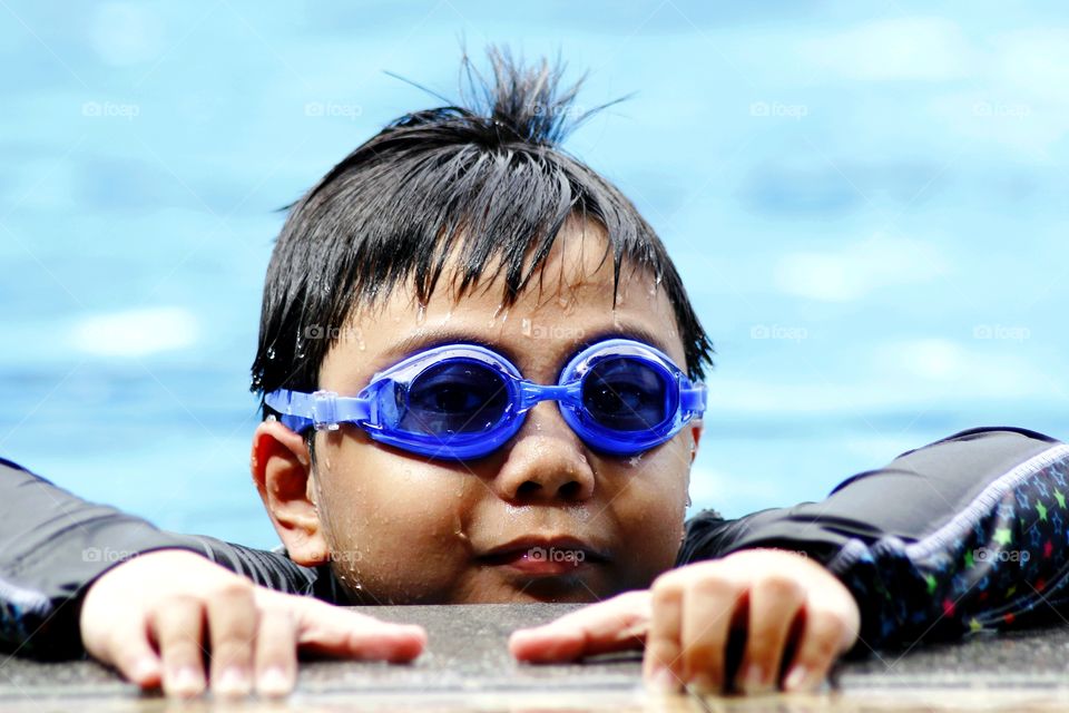 young boy with goggles in a swimming pool