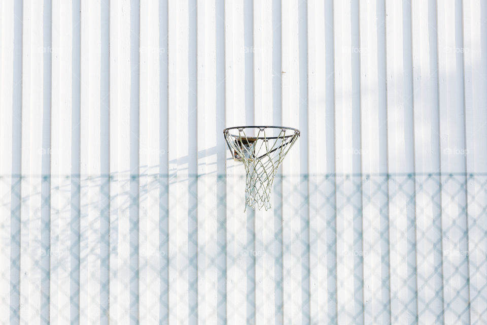 Minimalistic, basketball goal hoop on white wooden wall 