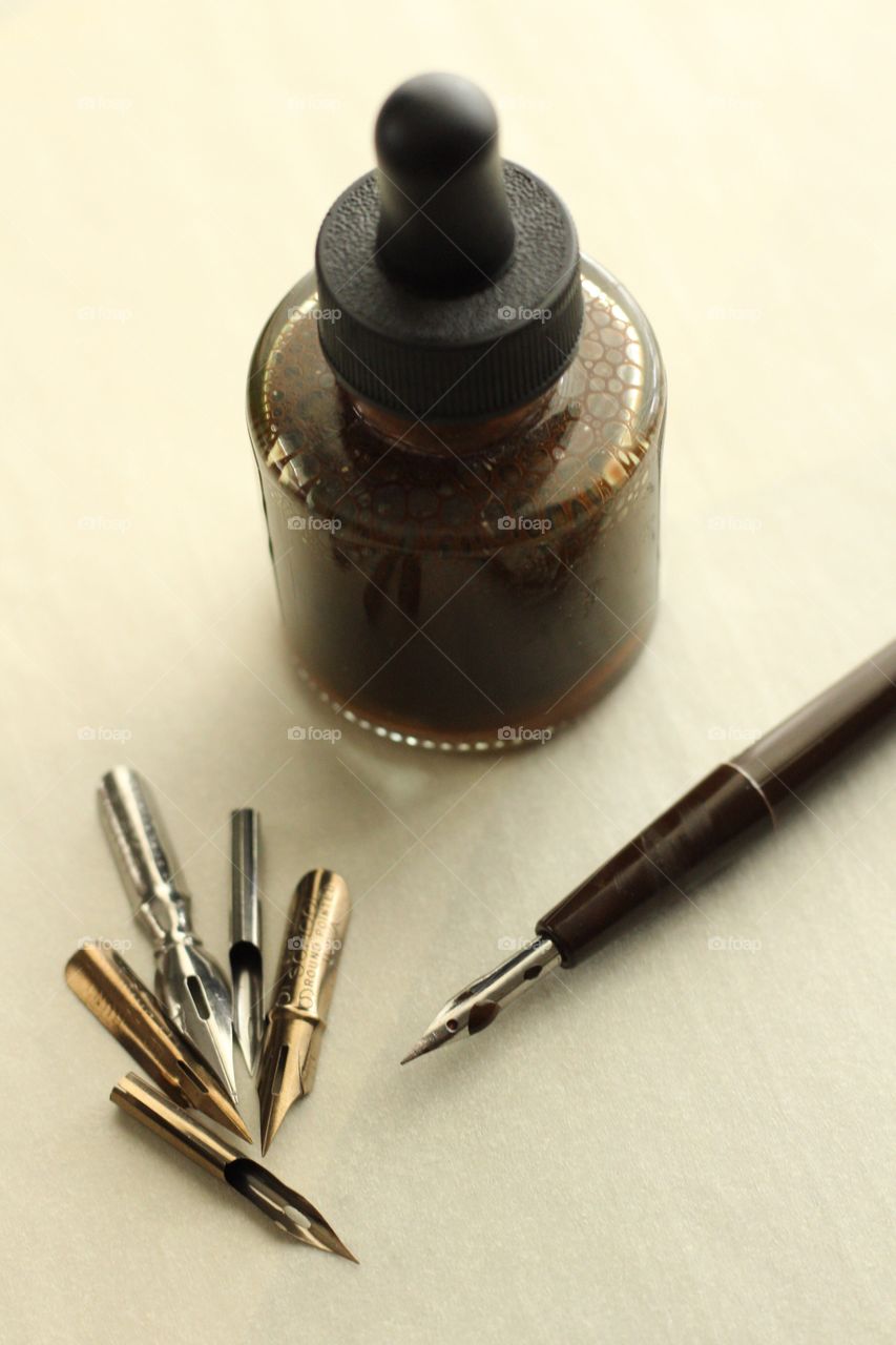 Arts & Crafts Supply - sepia ink bottle with various-sized metal nibs, nib in holder on parchment paper