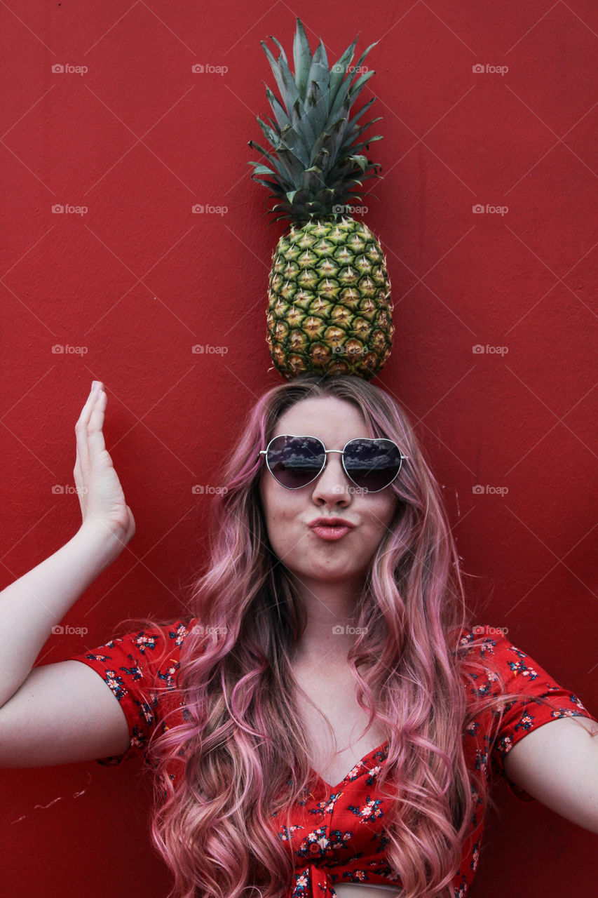 Portrait of a young woman carrying pineapple on her head