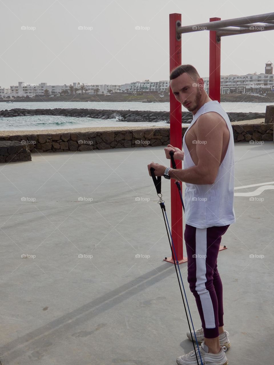 chico joven entrenando en la calle en exteriores, usando bandas elásticas y realizando ejercicios variados