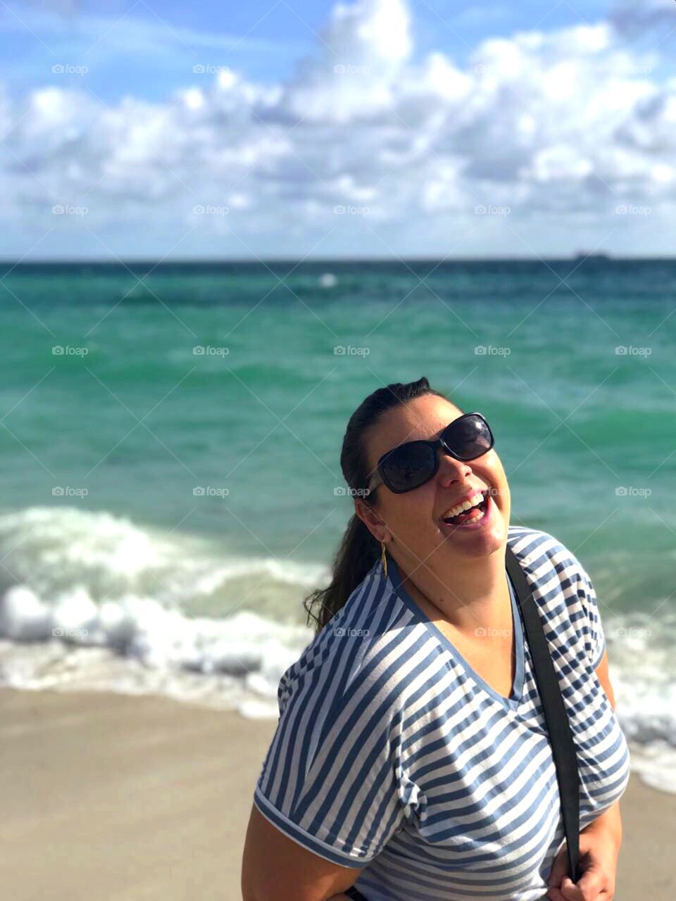 Brunette woman smiling on the beach.