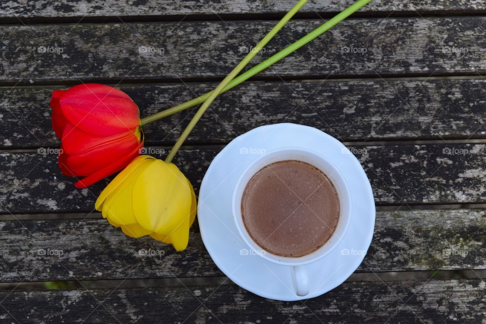 Cup of coffee and tulip flower on table