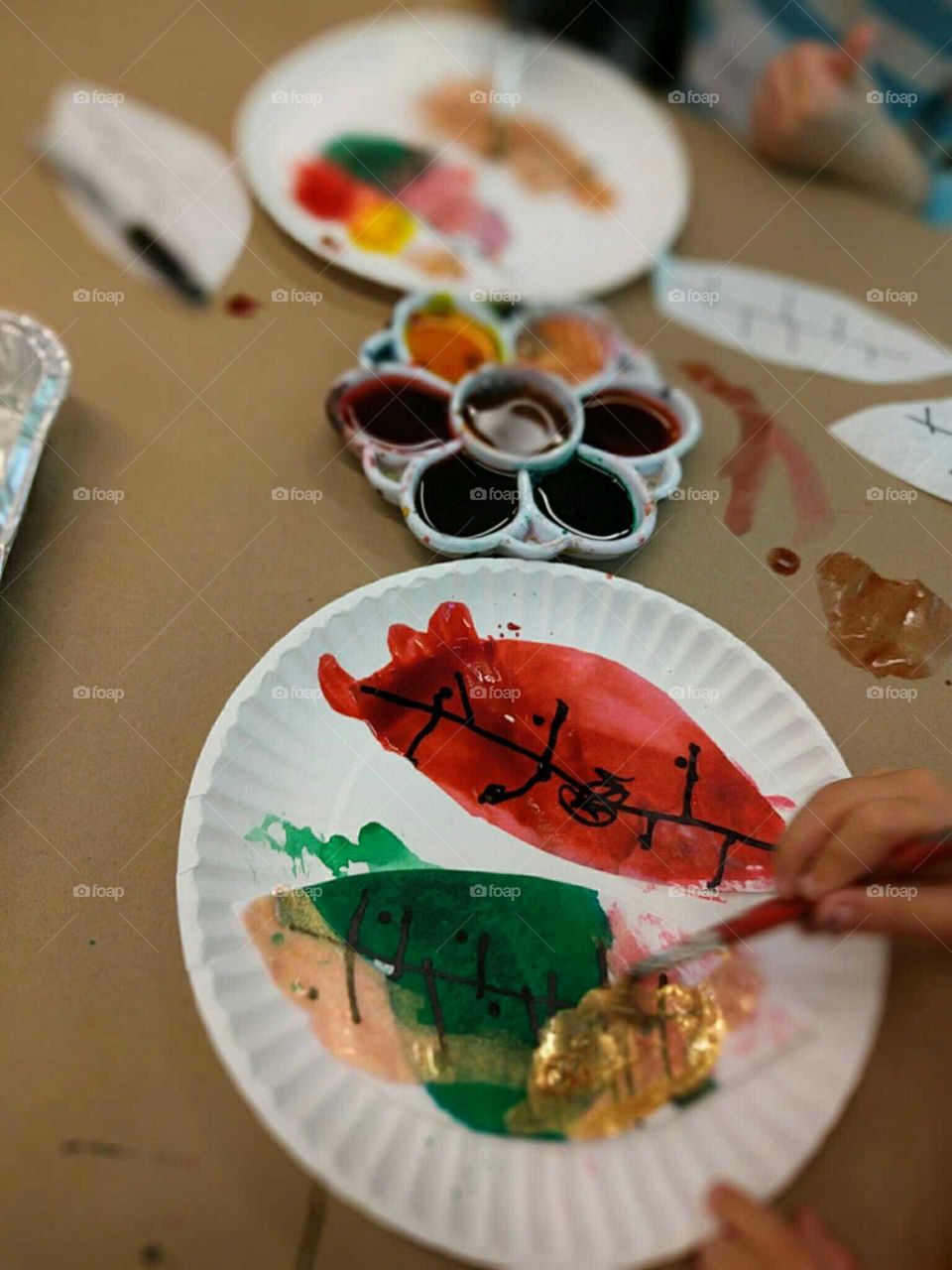 A small child adds gold to her painting.