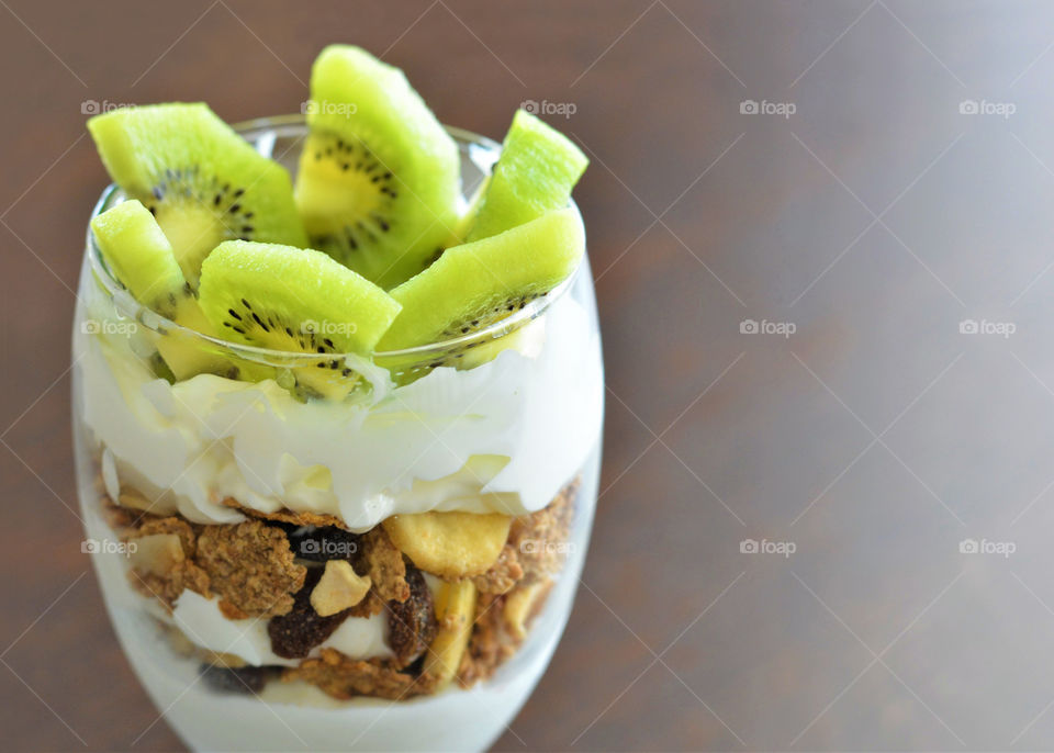 Greek yogurt, cereal and kiwi fruit in a glass. Healthy breakfast and dietary food. Loss weight meal . Copy space on the right side.