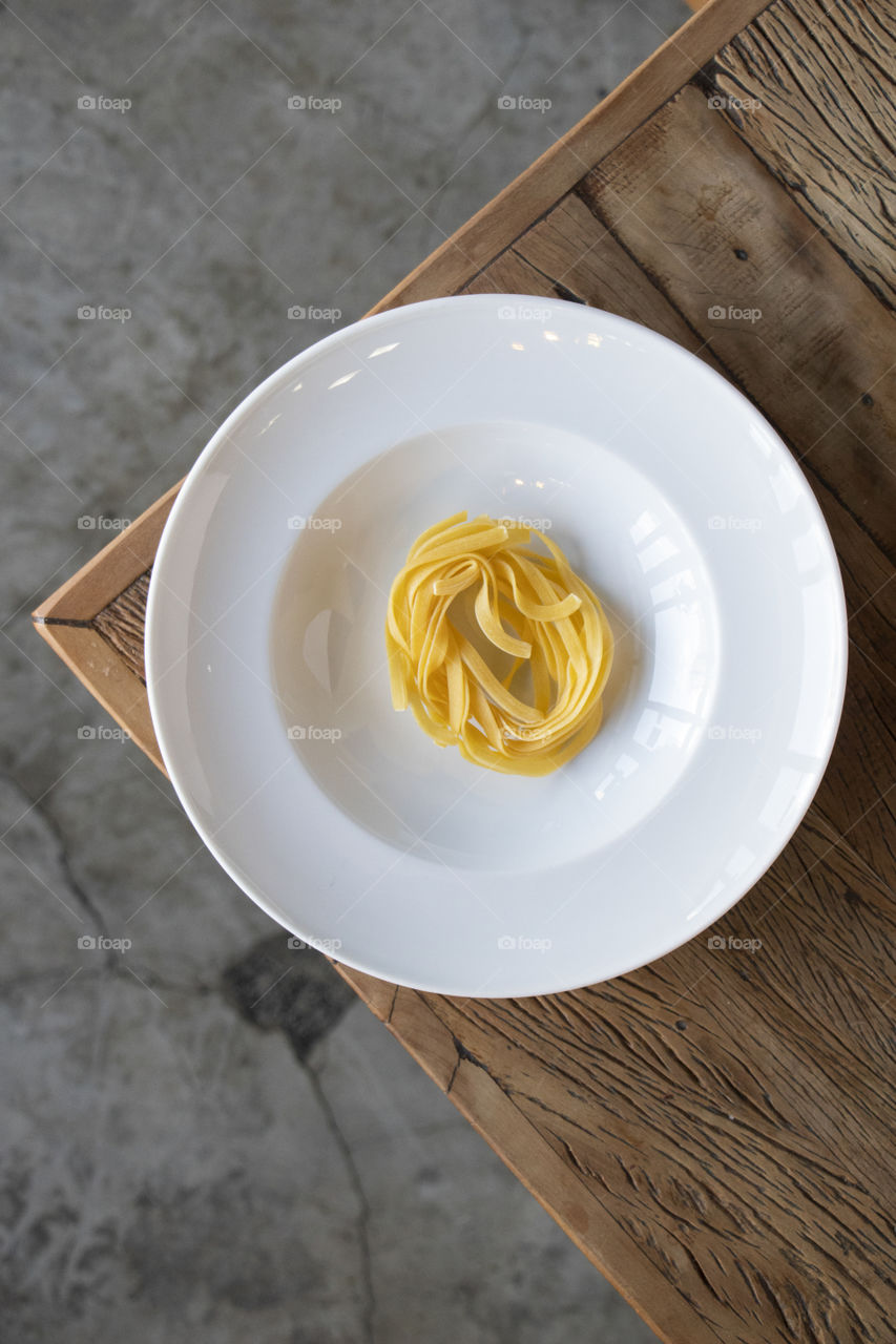 Brasil, Jundiaí, São Paulo, 2021. Pasta and plate forming two circles arranged on a rustic wooden table forming a triangle that further highlights the circles.