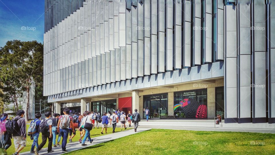 People walking towards the Hilmer Building of The University of New South Wales, Sydney, Australia. The Michael Crouch Innovation Centre is on the ground floor.