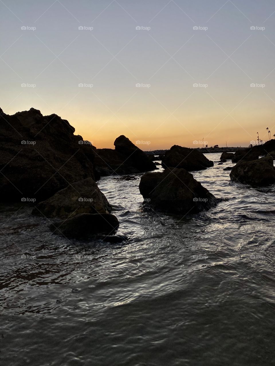 Sunset at Pirates Cove Beach with rocks in front of it