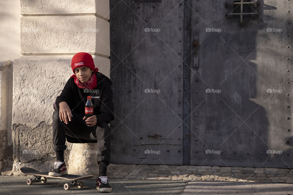 Teenager with a skateboard and Coca-Cola in his hands on the street