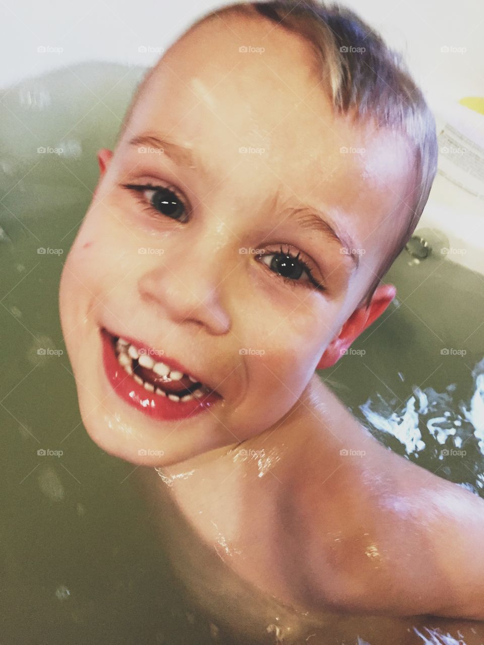 Very happy boy taking a bath